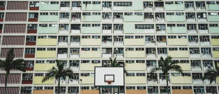 white and black portable basketball hoop near tall trees and concrete buildings at daytime